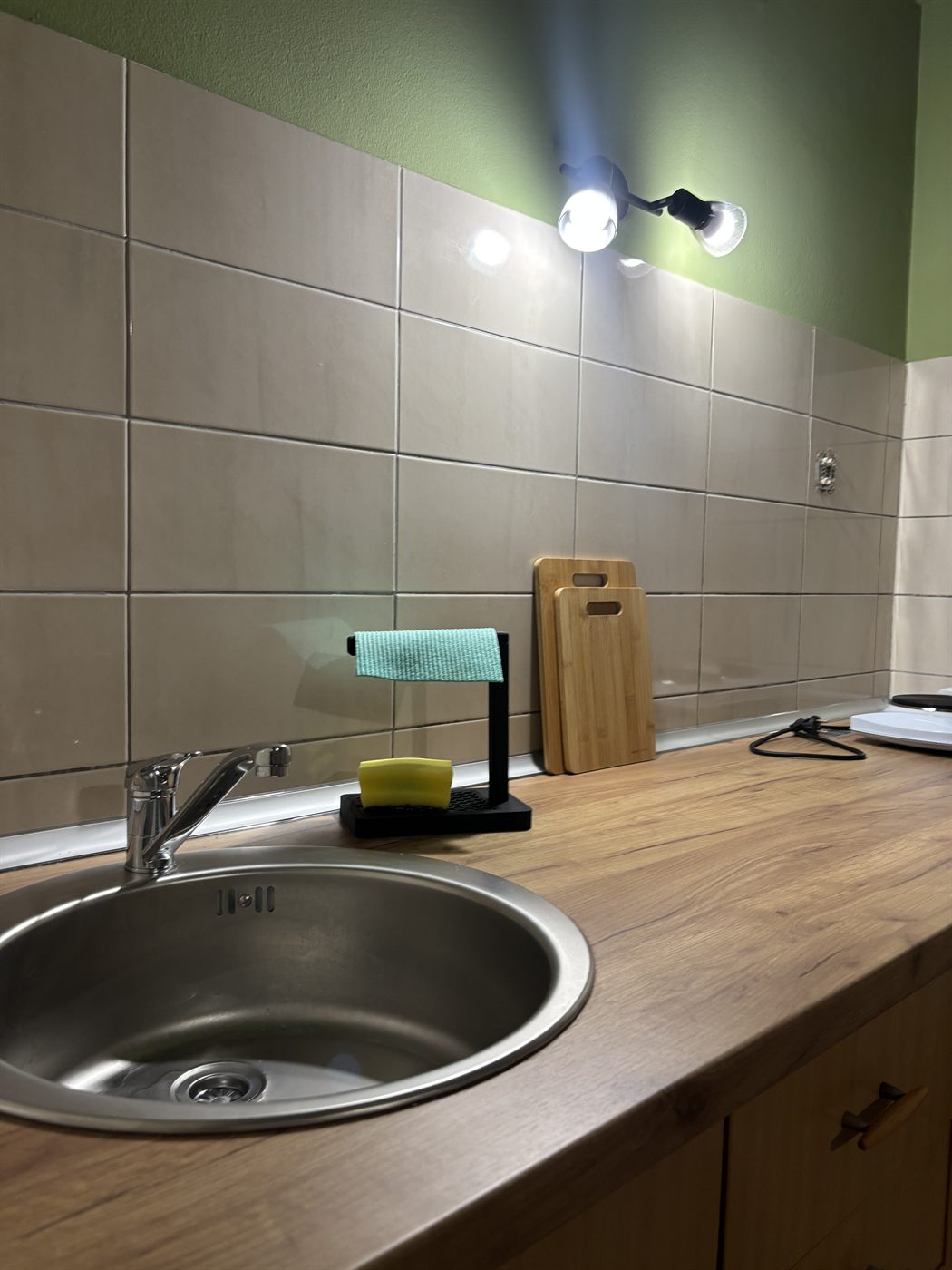 Detalj kuhinje — sudopera i radna površina sa daskom za sečenje